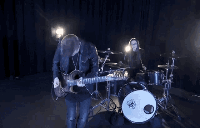 a man is playing a guitar and a woman is playing drums .