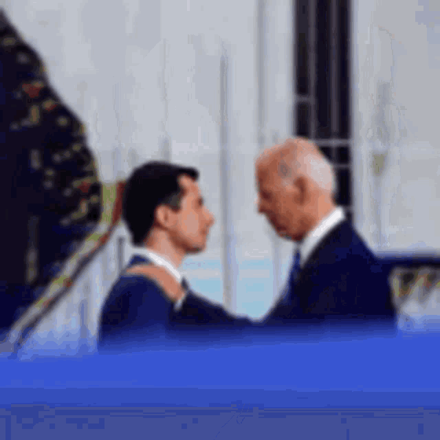 a man in a suit and tie is hugging another man in a suit .