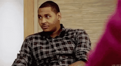 a man in a plaid shirt is sitting at a table looking at something .