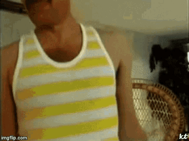 a man wearing a yellow and white striped tank top is standing in front of a chair ..