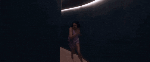 a woman in a purple dress is running down a hallway .