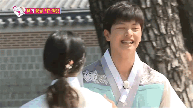 a man in a kimono is hugging a woman in a white shirt .