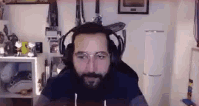 a man with a beard is wearing headphones and glasses while sitting in a chair in a room .