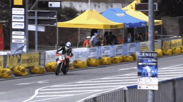 a man riding a motorcycle on a road with a sign that says genesis