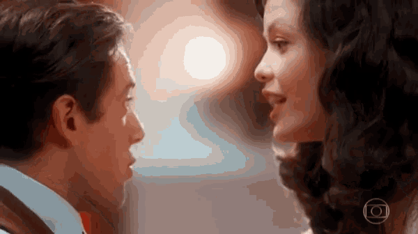 a man and a woman are looking into each other 's eyes with the letters o on the bottom right