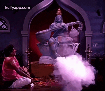a man is kneeling in front of a statue of a woman playing a musical instrument in a room .