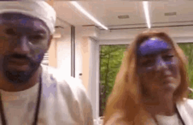 a man and a woman with their faces painted blue are standing next to each other .