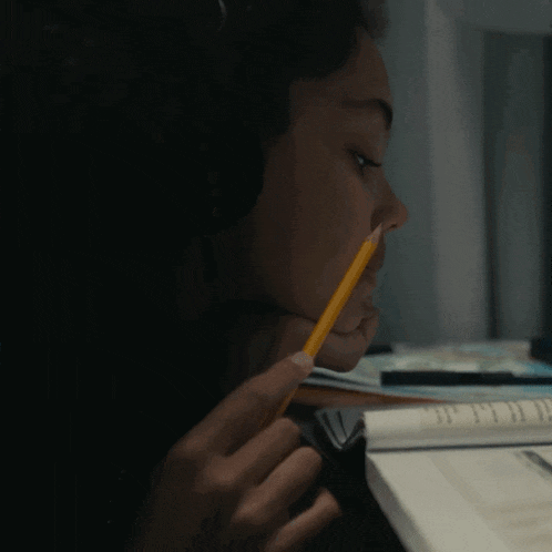 a woman is holding a pencil in her mouth while sitting at a desk