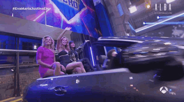 three women are sitting in a car with the word alba on the bottom left