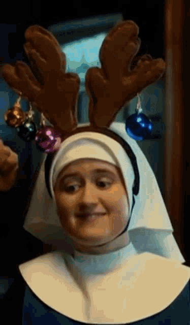 a nun is wearing a headband with reindeer antlers and bells .