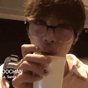a man wearing glasses is drinking from a cup with the name jochan written on it