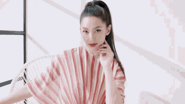 a woman wearing a pink and white striped shirt with red lipstick on her lips
