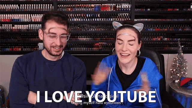 a man and a woman are sitting in front of a wall of nail polish and the man says i love youtube