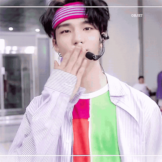 a young man wearing a headband and a microphone is kissing someone
