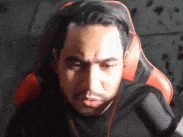 a man with a beard is sitting in a chair with headphones on his head .