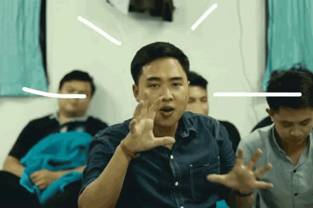 a man in a denim shirt is making a funny face with his hands outstretched