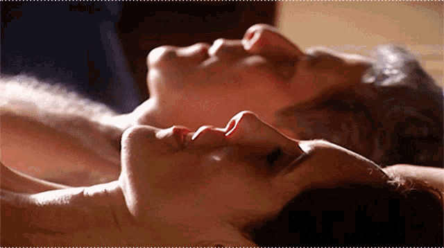 a man and a woman are laying on their backs with their heads together