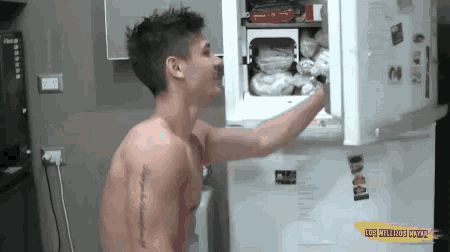 a shirtless man is reaching into a refrigerator with a yellow sticker that says ' ldp ' on it