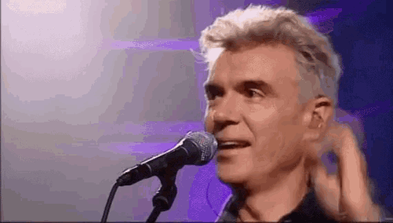 a man is singing into a microphone while adjusting his ear .