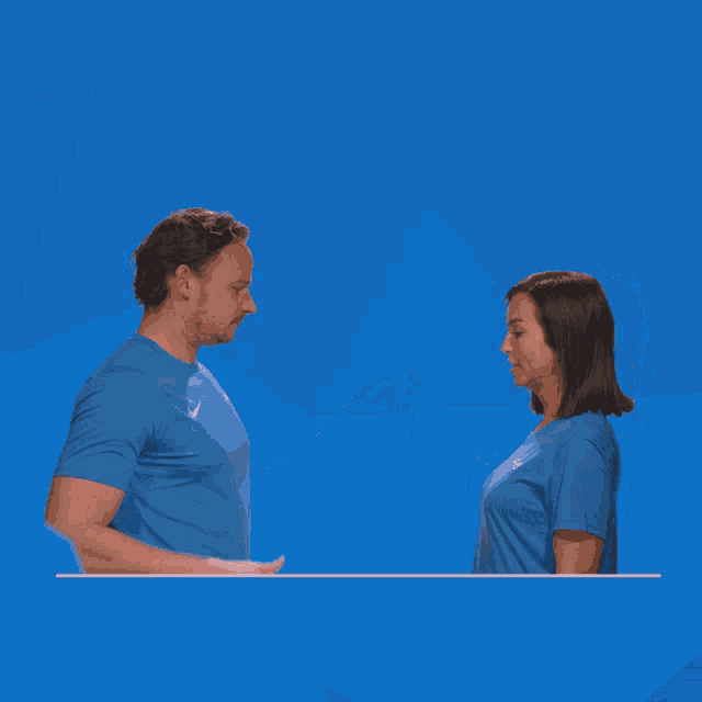 a man and a woman giving each other a fist bump in front of a blue background