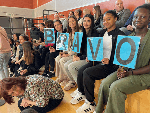 a group of people sitting on bleachers holding up signs that say bravo