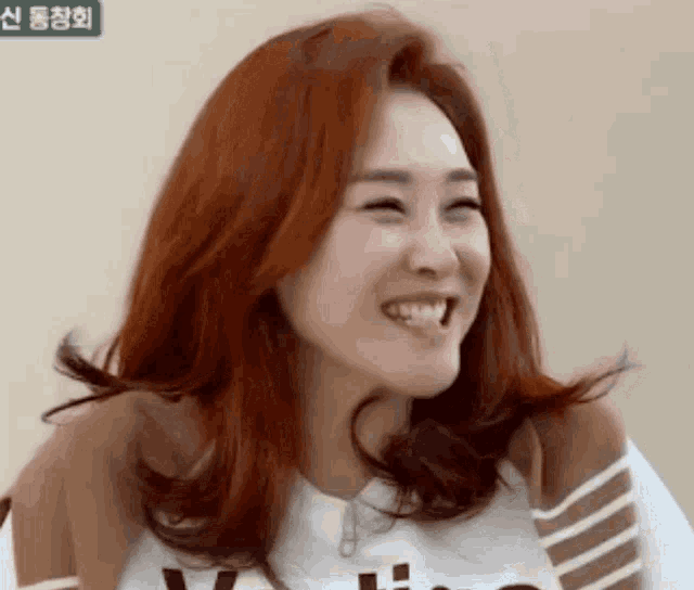 a woman with red hair is smiling and wearing a white shirt that says v