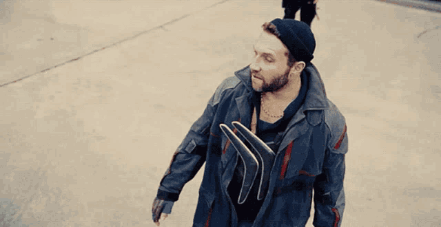 a man with a beard wearing a black hat and a chain around his neck