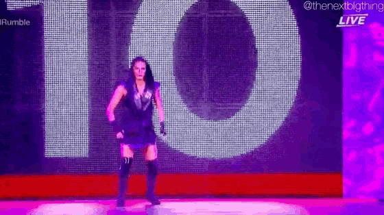a woman is standing on a stage in front of a large screen with the number 10 on it .