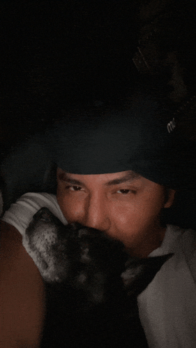a man wearing a black headband with the letter m on it kisses a black dog
