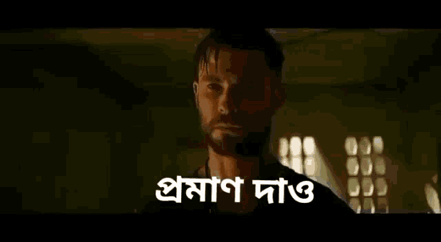 a man with a beard is standing in a dark room with a window in the background .