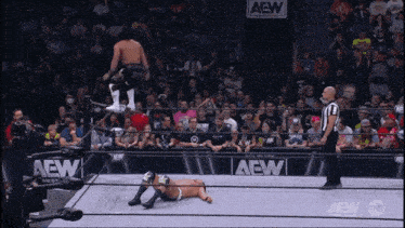 a wrestler is jumping over another wrestler in a ring that says aew on it
