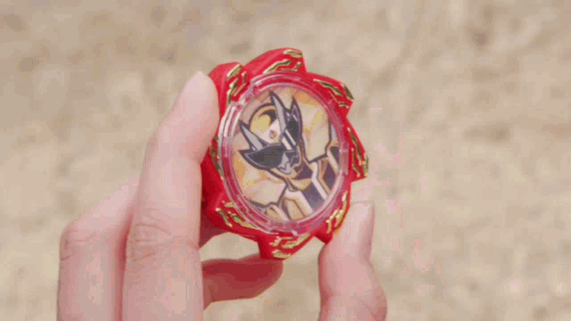 a person is holding a red toy that has a picture of a knight on it