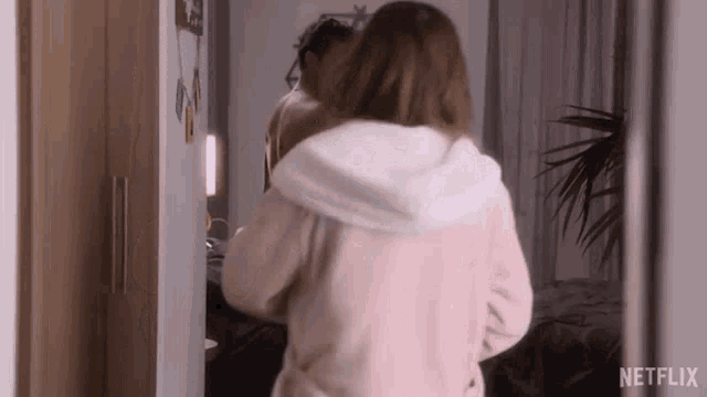 a woman in a bathrobe is standing next to a man in a bathrobe in front of a mirror .