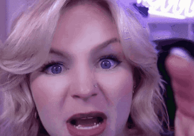 a woman with a nose ring is making a funny face with her mouth open