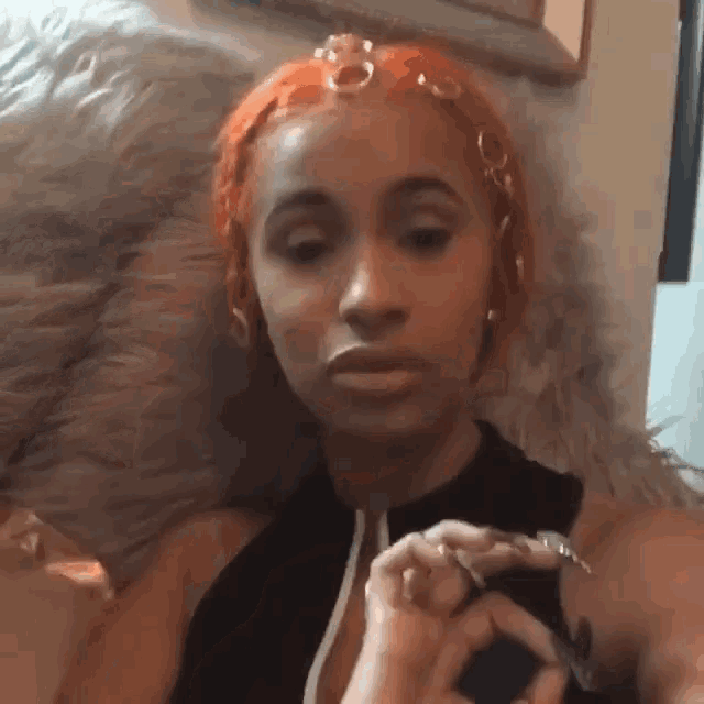 a woman with red hair is sitting on a couch with a furry pillow .
