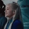 a woman in a blue jacket is smiling while sitting in a crowd .