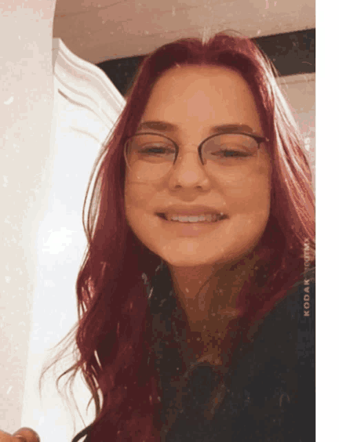 a woman with red hair wearing glasses and a kodak watermark