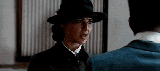 a man and a woman are standing next to each other and the woman is wearing a hat .
