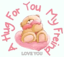 a teddy bear is sitting on a heart shaped pillow .