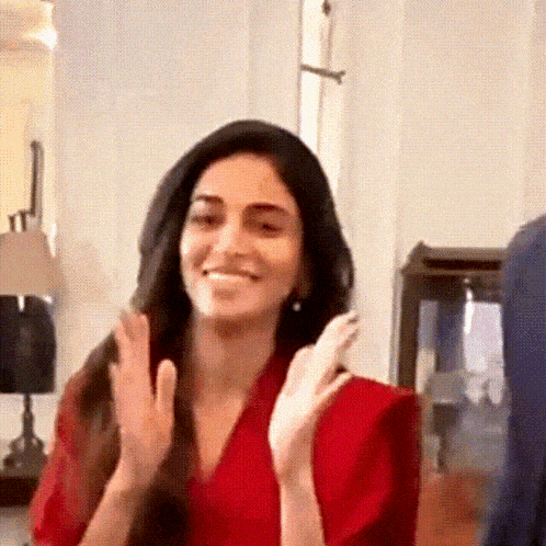 a woman in a red shirt is clapping her hands .
