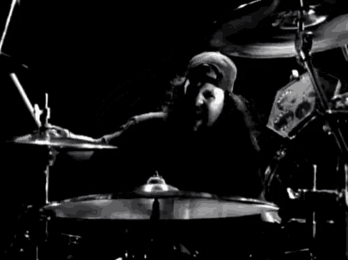 a black and white photo of a man playing a drum set