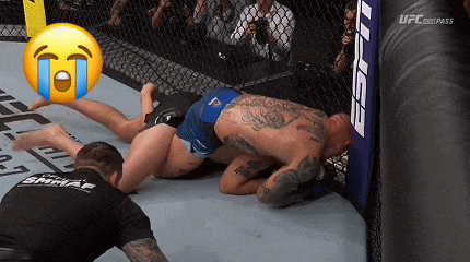 two men are wrestling in a ufc cage with a crying face in the background