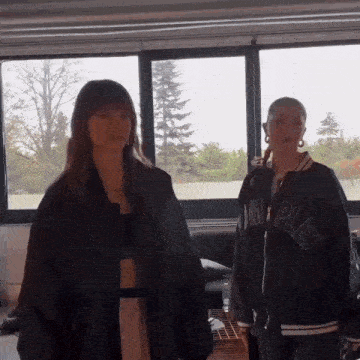 two women standing next to each other in front of a window wearing jackets that say complex