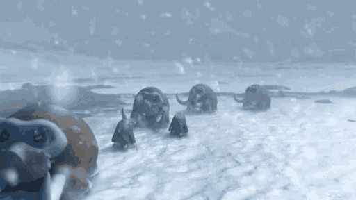 a group of mammoths are walking through the snow in a snowy field .