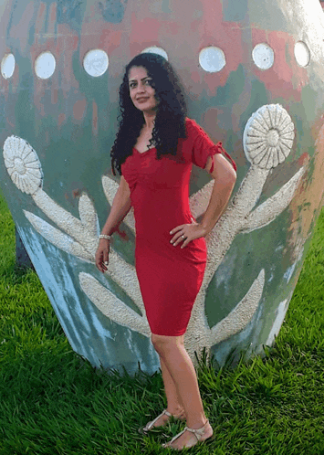 a woman in a red dress is standing in front of a sculpture