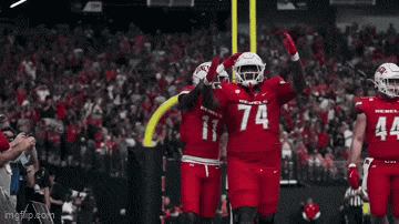 a football player with the number 74 on his jersey is celebrating with his teammates