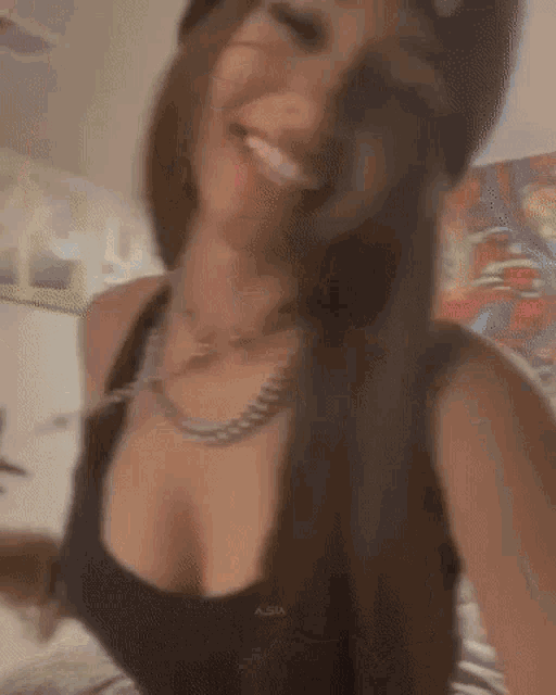 a woman wearing a hat and a black tank top is smiling and looking at the camera .