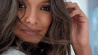 a close up of a woman 's face with her hair flying in the wind .