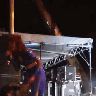 a woman in a purple dress is singing into a microphone at a concert