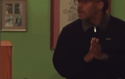 a man wearing glasses and a black jacket is talking
